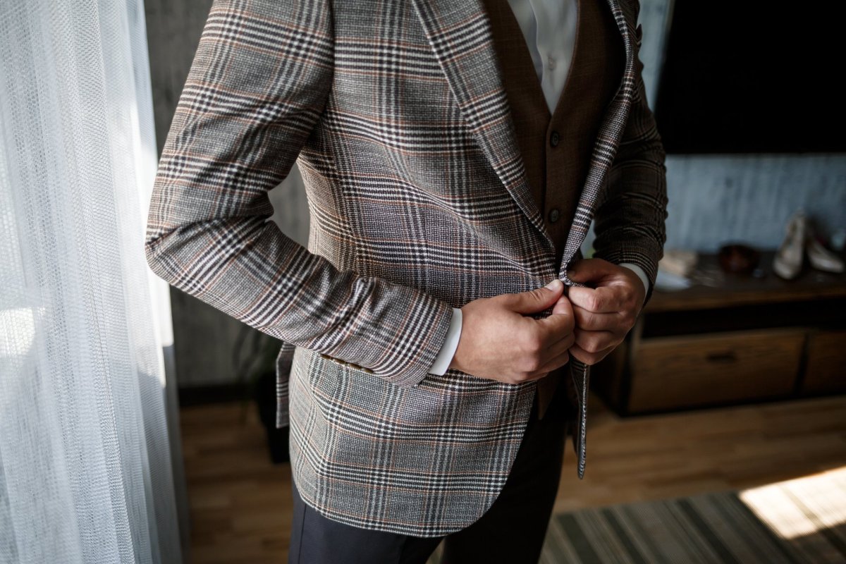 Mann knoepft Sakko zu